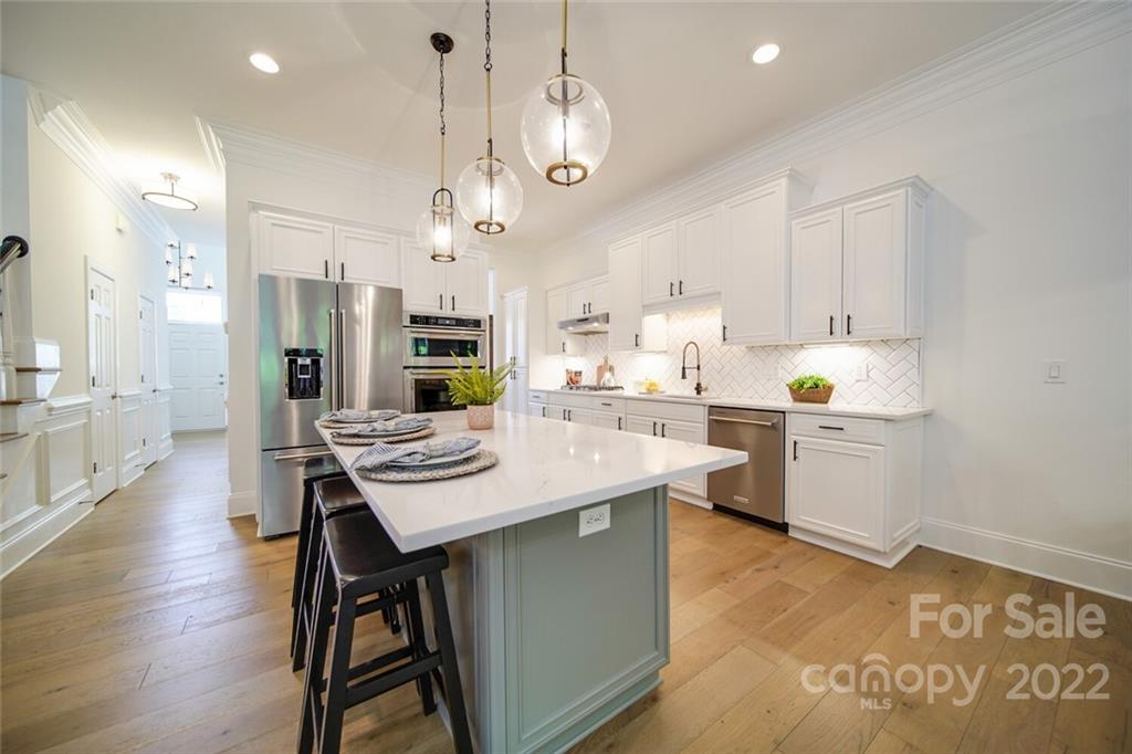 6309 Wakehurst Road Charlotte, NC 28226 - Photo 14 of 48 a kitchen with stainless steel appliances kitchen island granite countertop a table chairs and a refrigerator