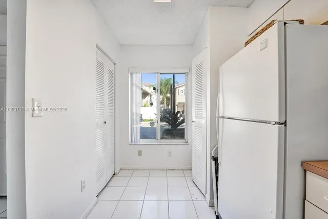 a kitchen with a sink a refrigerator and white cabinets