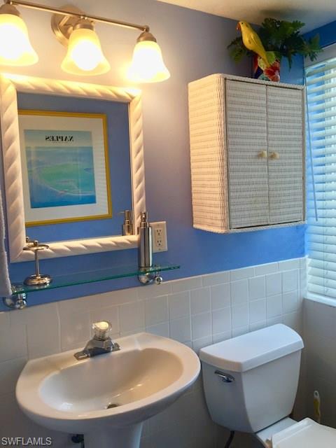 175 5th Avenue South, Unit 104 Naples, FL 34102 - Photo 7 of 9 a bathroom with a toilet a sink and mirror