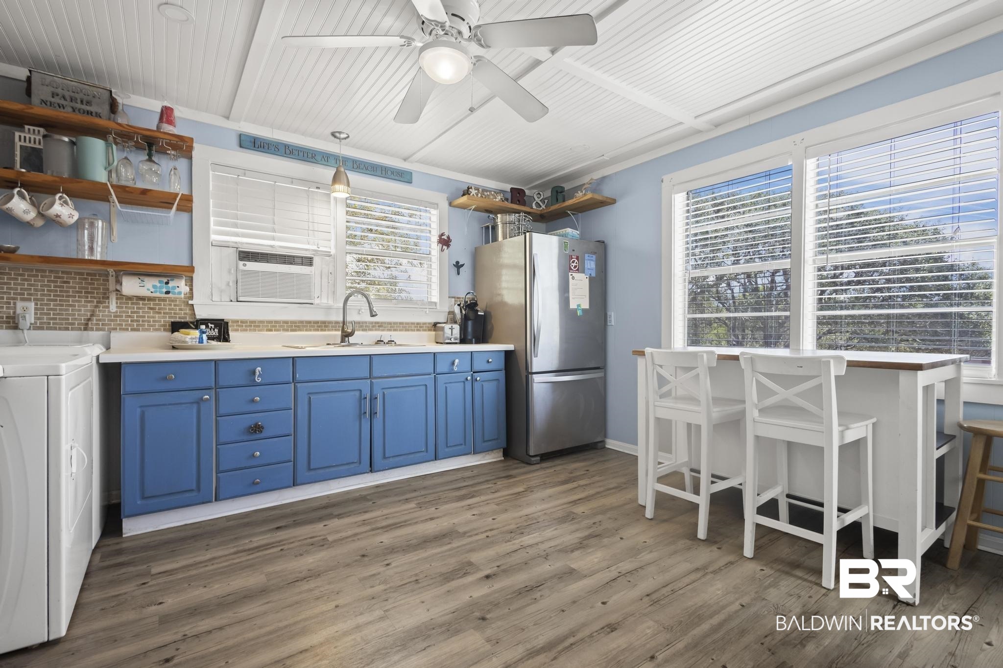 562 Veterans Road Gulf Shores, AL 36542 - Photo 6 of 32 Kitchen with freestanding refrigerator, open shelves, blue cabinetry, a sink, and cooling unit