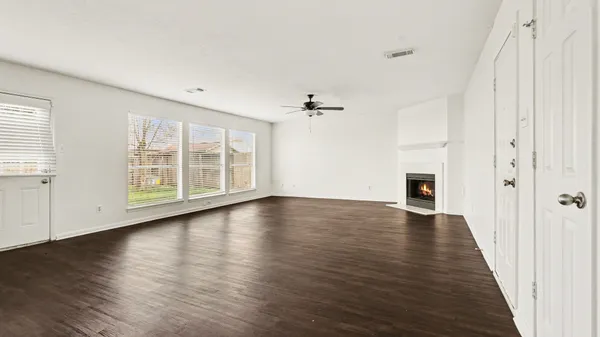 an empty room with wooden floor cabinet and windows