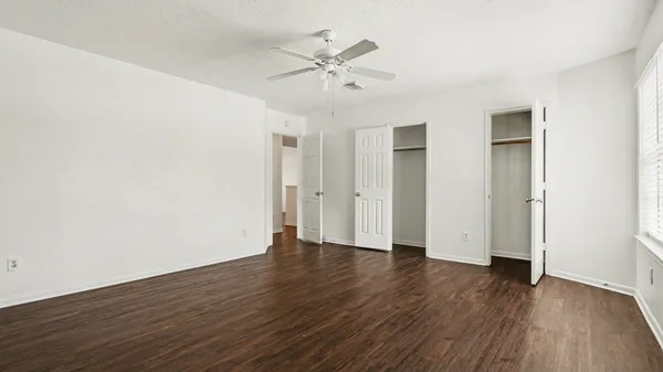an empty room with wooden floor and a ceiling fan