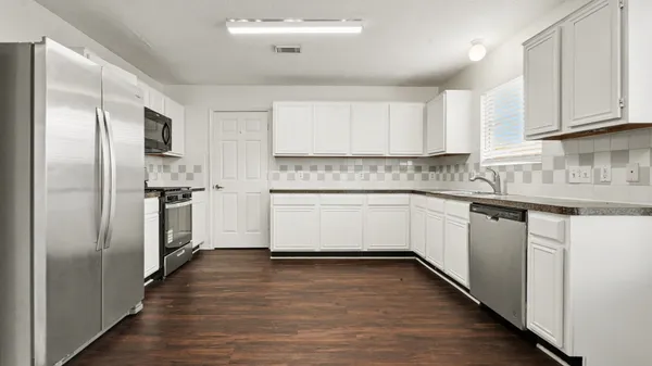 a kitchen with a refrigerator sink and cabinets