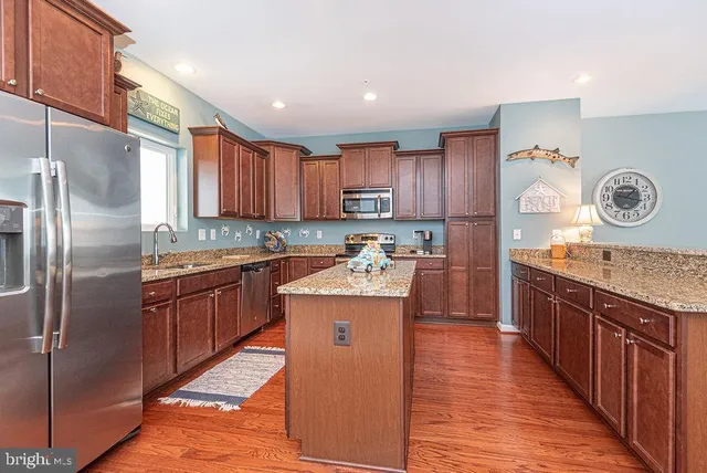 a kitchen with stainless steel appliances granite countertop a stove top oven a sink dishwasher and wooden cabinets with wooden floor