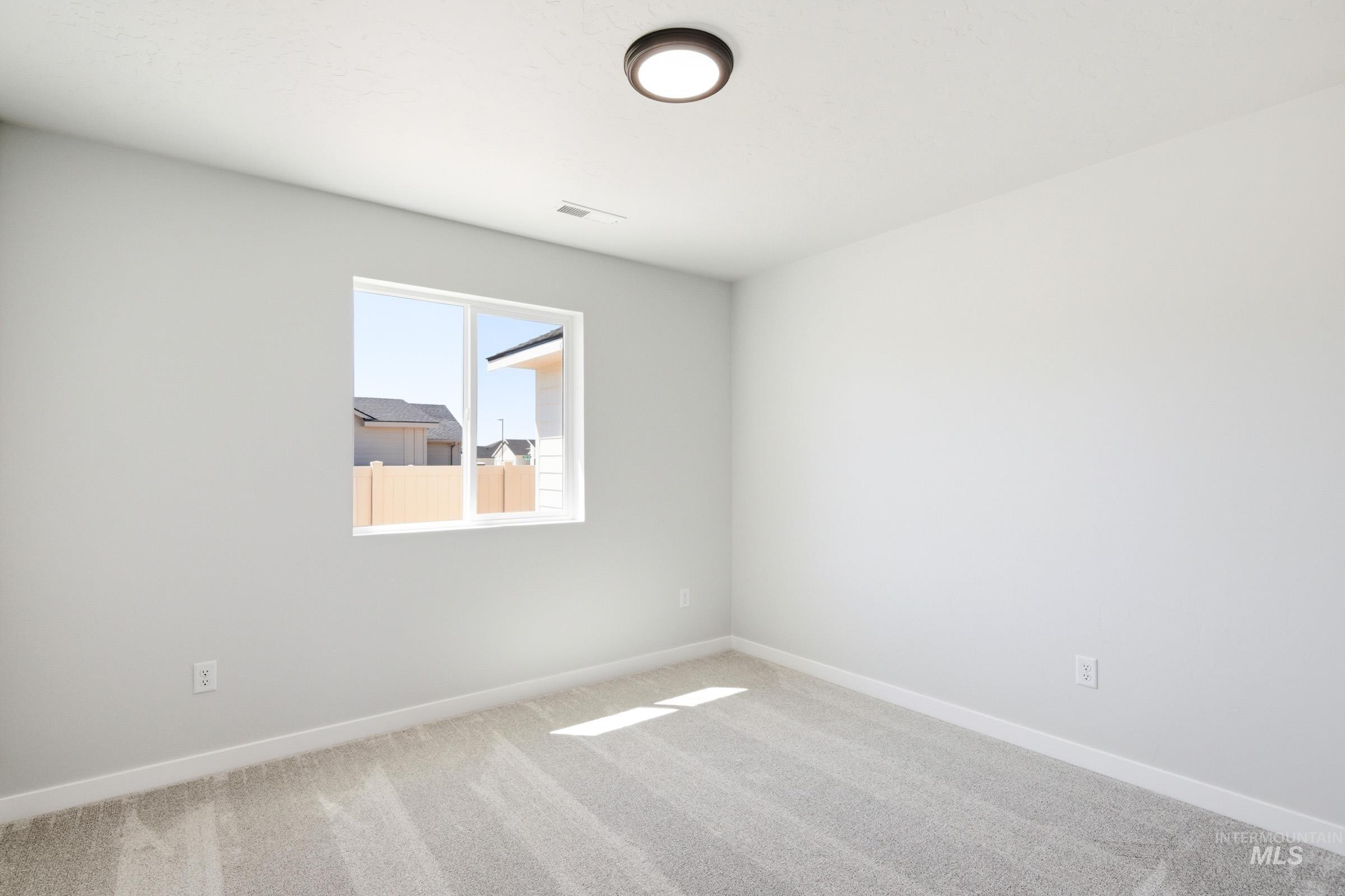 12817 Decatur Street Nampa, ID 83651 - Photo 15 of 19 Bright room featuring light gray walls, plush gray carpet, a white framed window, white baseboards, and a contemporary flush-mount ceiling light