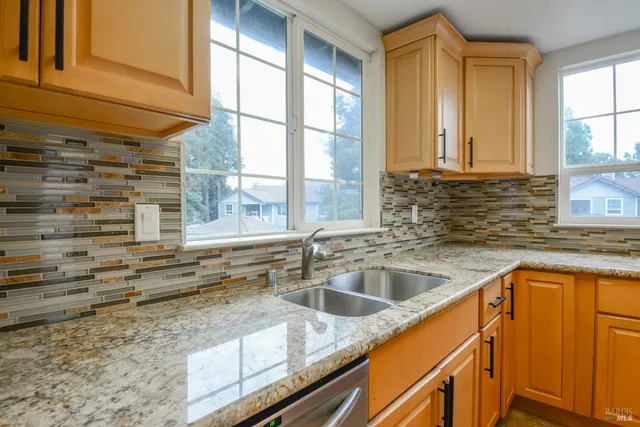 a kitchen with stainless steel appliances granite countertop a sink and a window