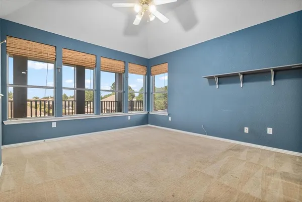 a view of an empty room with a chandelier fan and a window