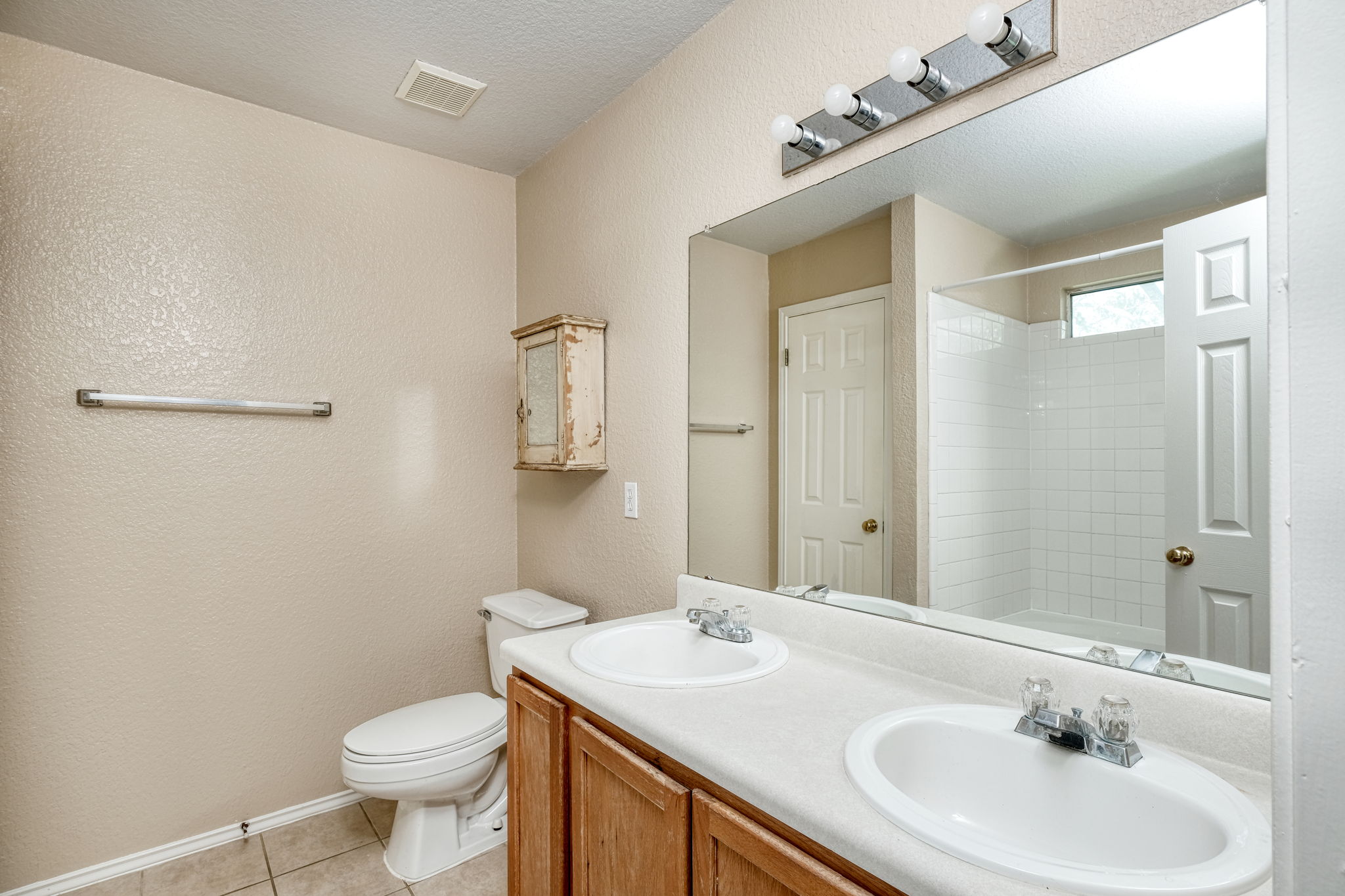124 Hunter Rex Way Kyle, TX 78640 - Photo 8 of 14 Bathroom featuring a double vanity with integrated sinks, white countertops, and wood-finish cabinetry