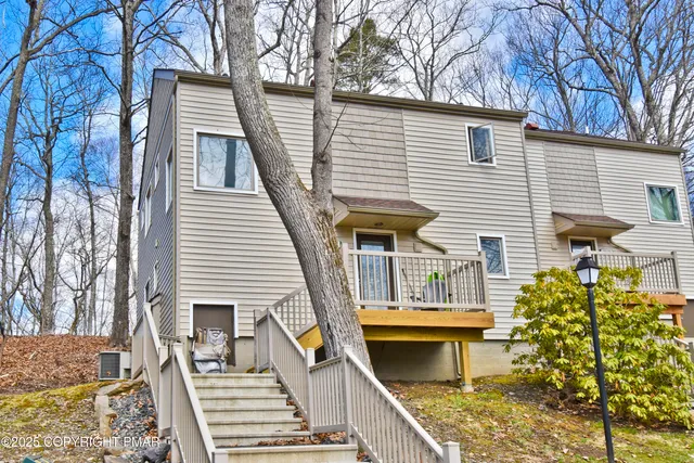 a view of a white house with a small yard and large tree
