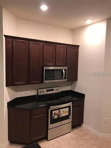 a kitchen with granite countertop white cabinets and stainless steel appliances