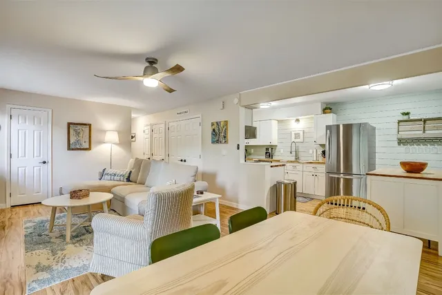 a living room with furniture a refrigerator and kitchen view