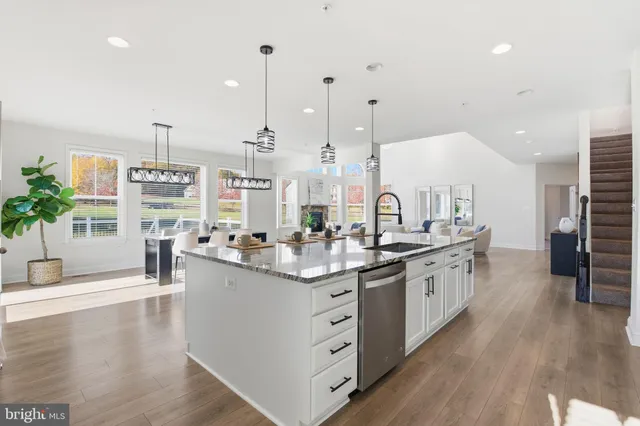 a kitchen with stainless steel appliances kitchen island granite countertop a stove a sink a refrigerator a center island and a wooden floor