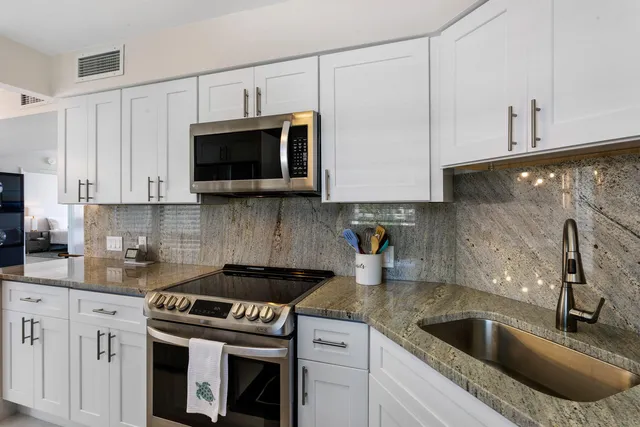 a kitchen with granite countertop a sink stove and microwave