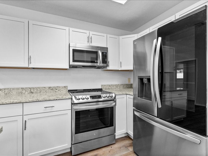 6631 Ambler Drive Spring, TX 77379 - Photo 5 of 37 a kitchen with stainless steel appliances granite countertop white cabinets a microwave a sink and a refrigerator