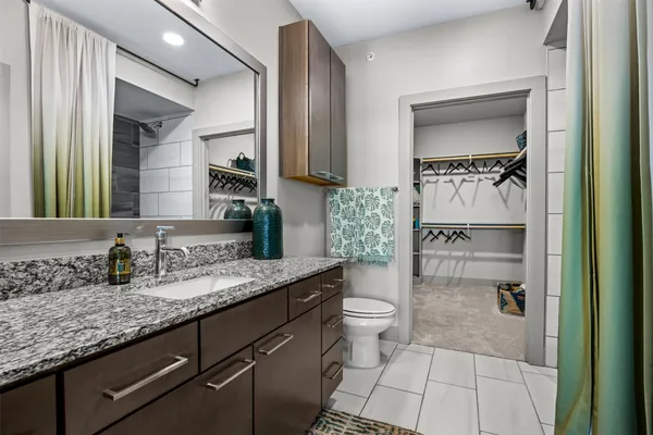 a bathroom with a granite countertop sink a toilet and a mirror