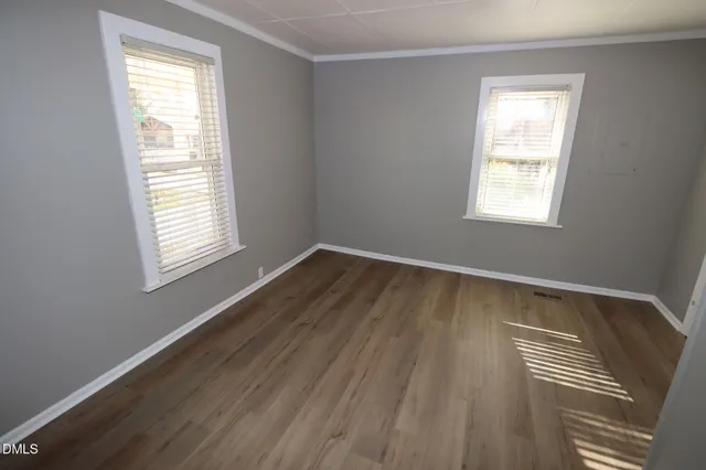 a view of an empty room with wooden floor and a window