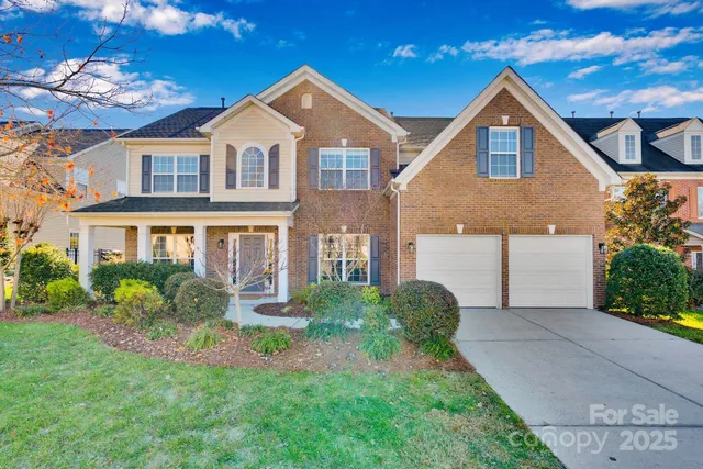 a front view of a house with a yard and potted plants