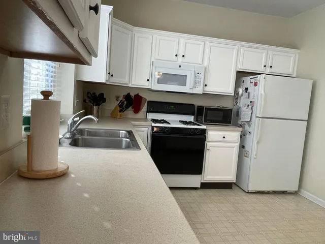 a kitchen with a refrigerator a stove a sink and white cabinets
