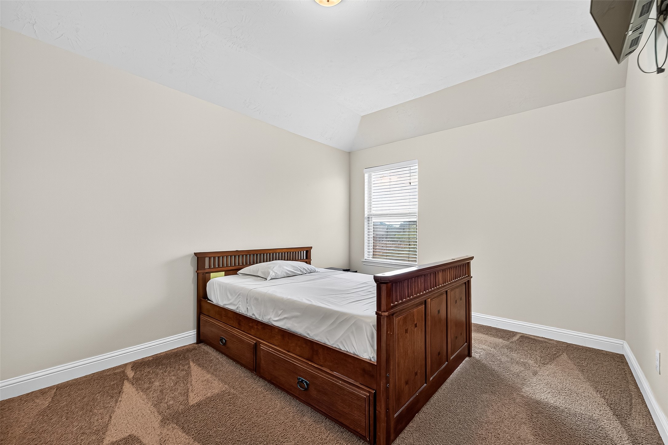8107 Lockridge Terrace Lane Cypress, TX 77433 - Photo 41 of 50 This charming secondary bedroom offers comfort and privacy, complete with plush carpeting, elevated ceilings, and natural light streaming through the window—perfect for family, guests, or a personalized home office retreat.