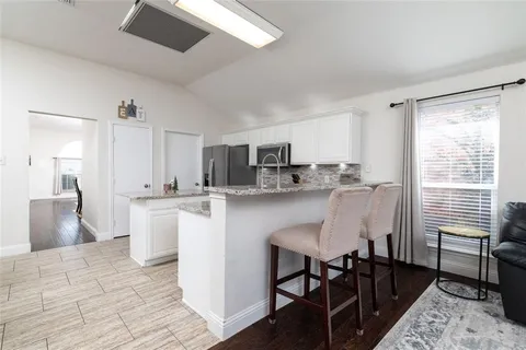 a kitchen with kitchen island a dining table chairs and white cabinets