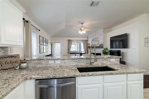 a kitchen with granite countertop a sink and white cabinets