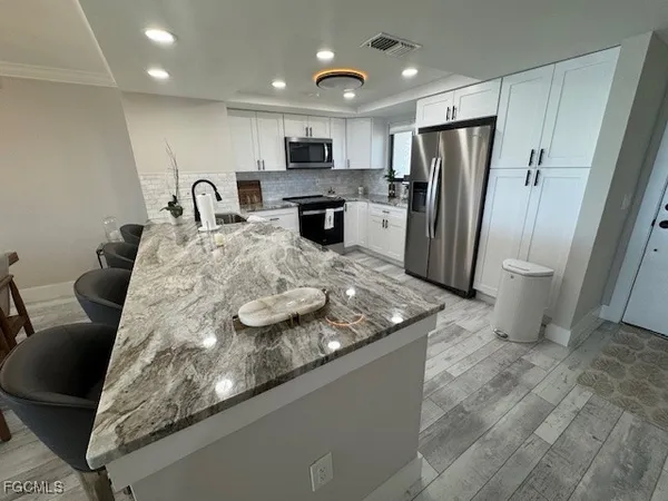a kitchen with stainless steel appliances granite countertop a sink refrigerator and cabinets