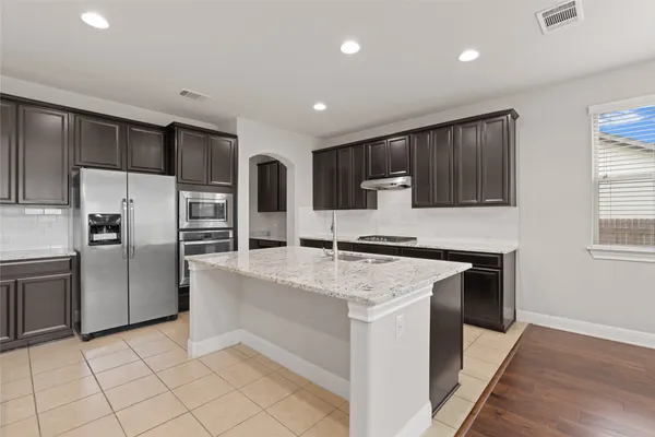a kitchen with granite countertop stainless steel appliances a sink stove and refrigerator