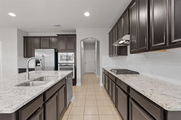 a kitchen with stainless steel appliances granite countertop a sink stove and cabinets