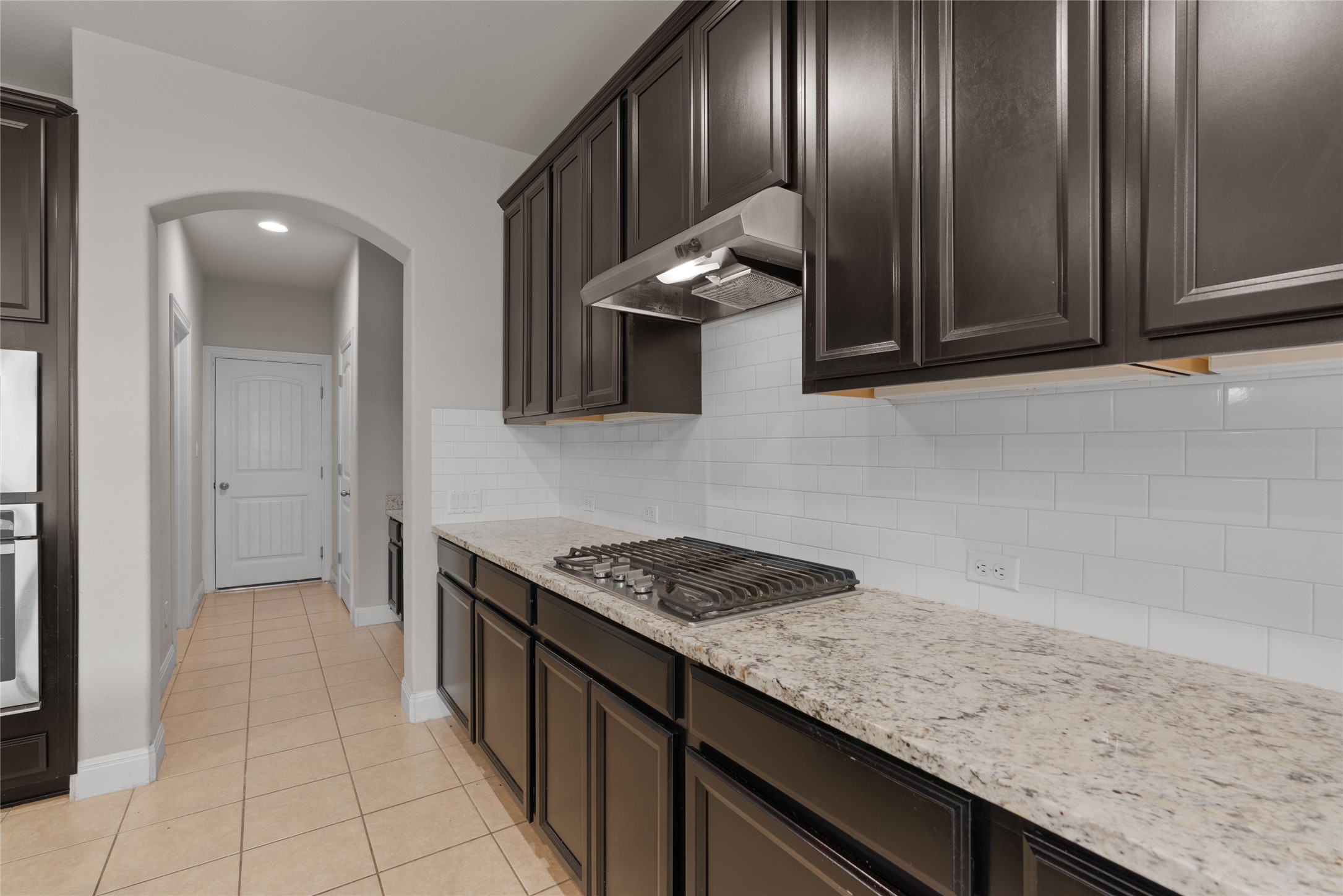 15601 Cabrillo Way Austin, TX 78738 - Photo 13 of 32 Kitchen with dark wood-finish cabinetry, light speckled countertops, and a white subway tile backsplash