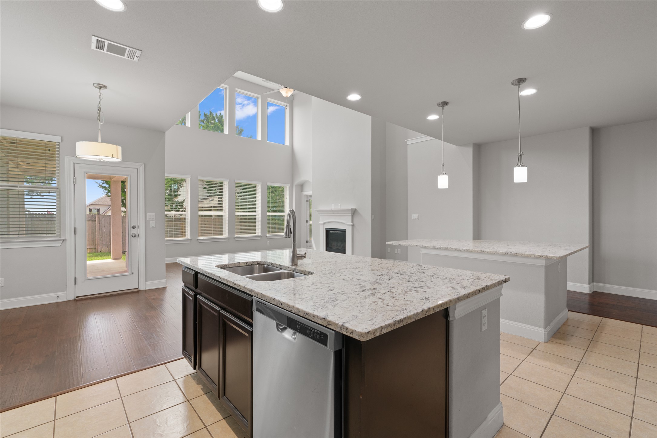 15601 Cabrillo Way Austin, TX 78738 - Photo 14 of 32 Kitchen island featuring a dual basin sink, integrated dishwasher, and granite countertop