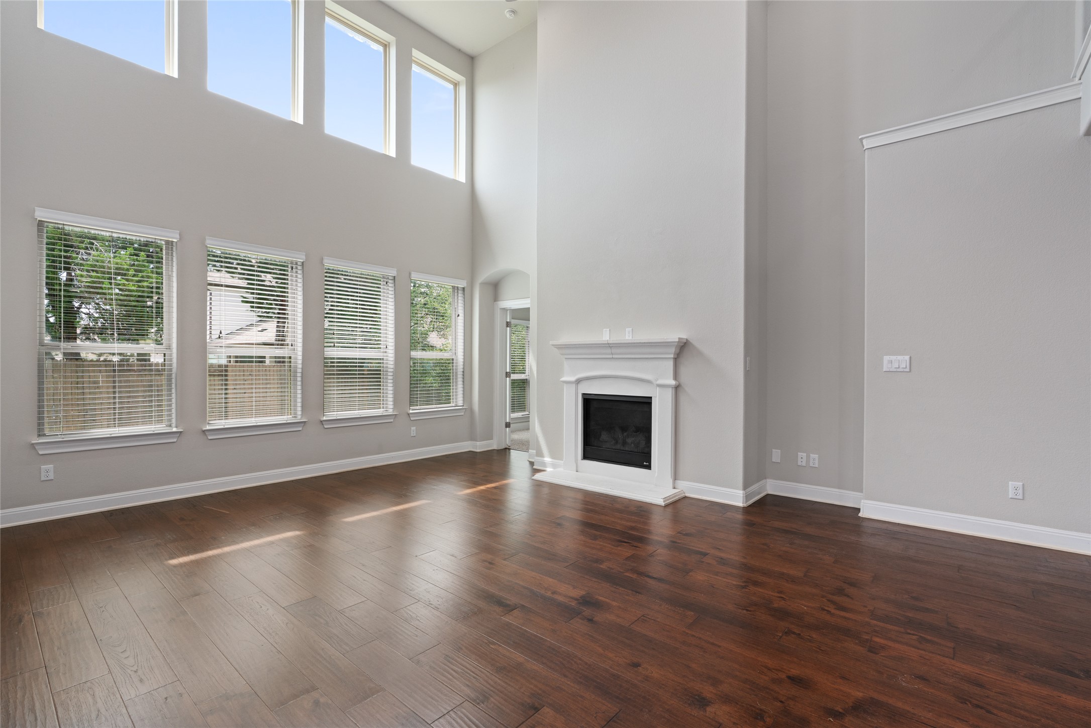 15601 Cabrillo Way Austin, TX 78738 - Photo 18 of 32 Living area featuring soaring ceilings, a white-mantled fireplace, abundant natural light from multiple windows, and rich wood-finish flooring