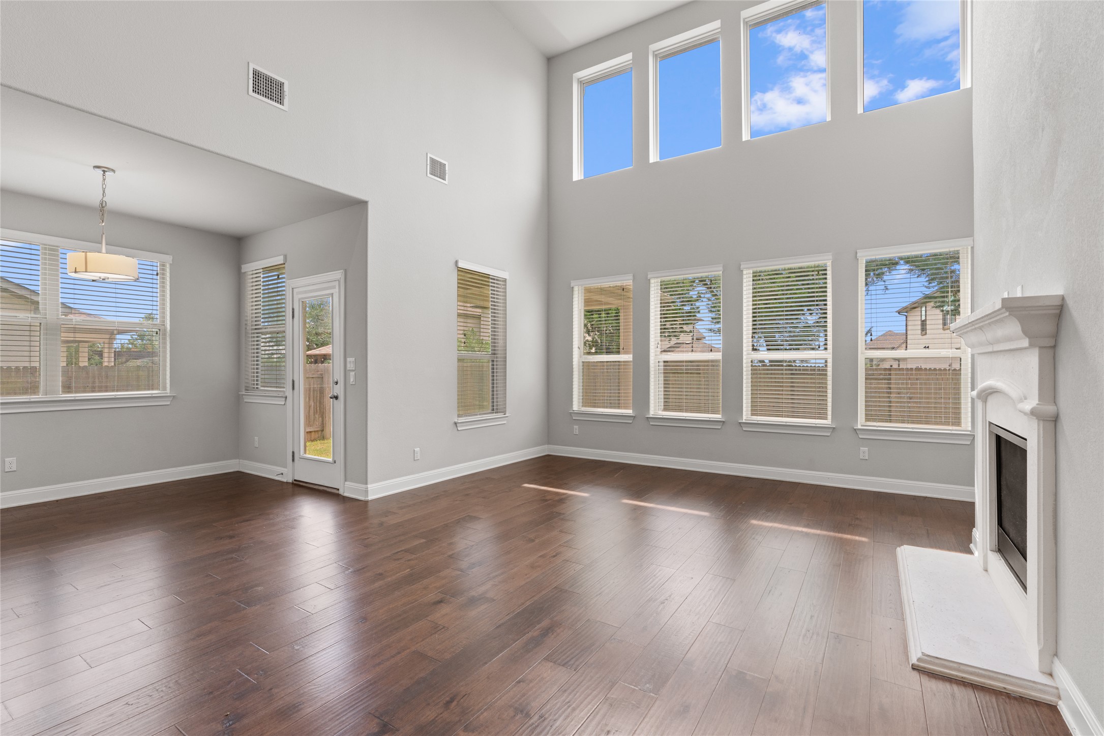 15601 Cabrillo Way Austin, TX 78738 - Photo 21 of 32 Living area featuring wood-finish flooring, a two-story ceiling, and a prominent fireplace with a white mantel