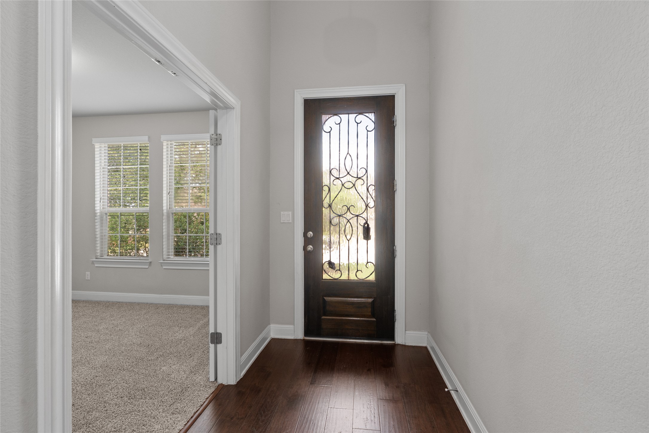 15601 Cabrillo Way Austin, TX 78738 - Photo 3 of 32 Entry foyer featuring wood-finish flooring, a dark wood entry door with decorative ironwork, and a neutral wall color