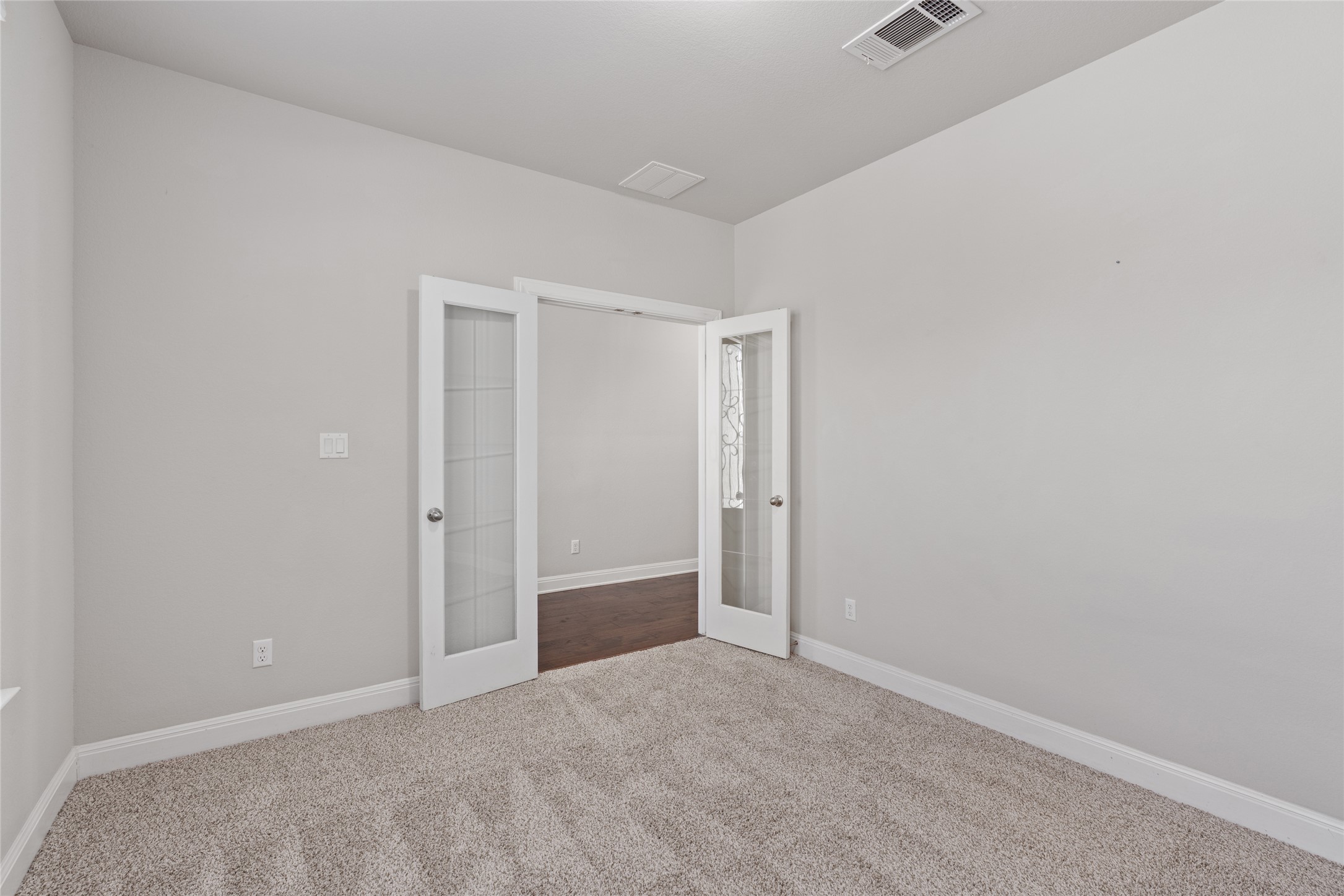 15601 Cabrillo Way Austin, TX 78738 - Photo 5 of 32 Carpeted room featuring light gray walls, white baseboards, and a doorway with twin frosted glass panel doors