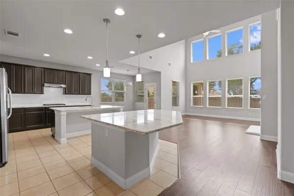 a large kitchen with kitchen island a sink a center island stainless steel appliances and a fireplace