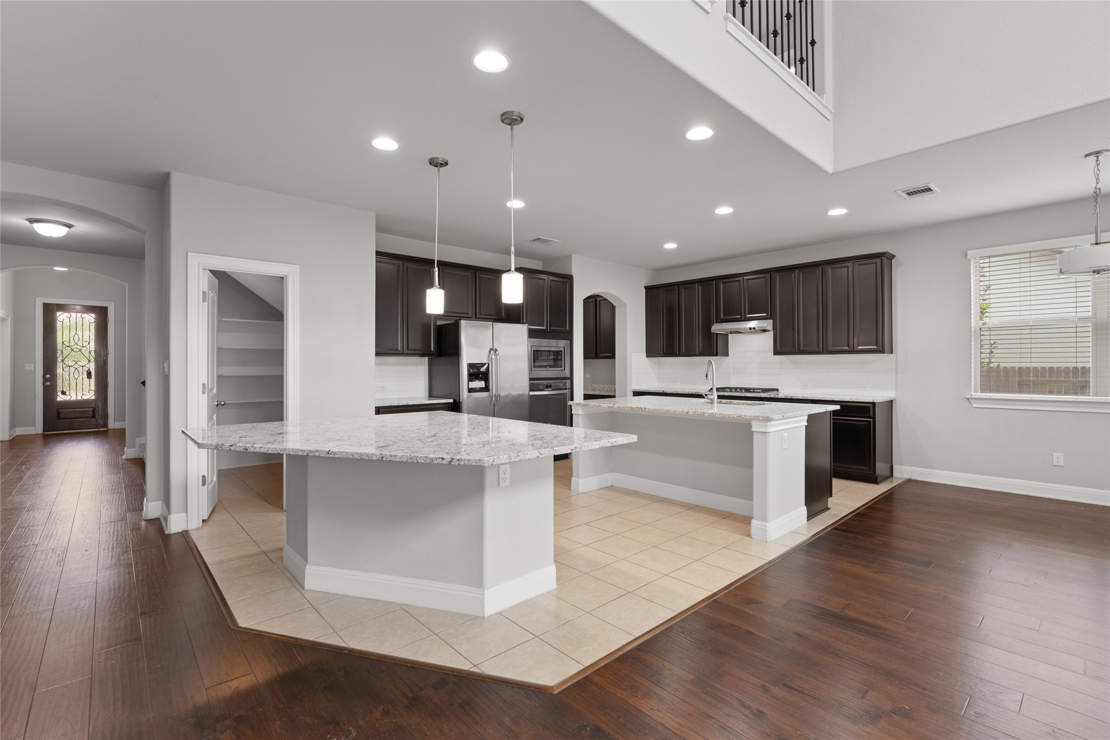 15601 Cabrillo Way Austin, TX 78738 - Photo 10 of 32 Kitchen area featuring two islands with light-toned countertops, dark cabinetry, and integrated stainless steel appliances