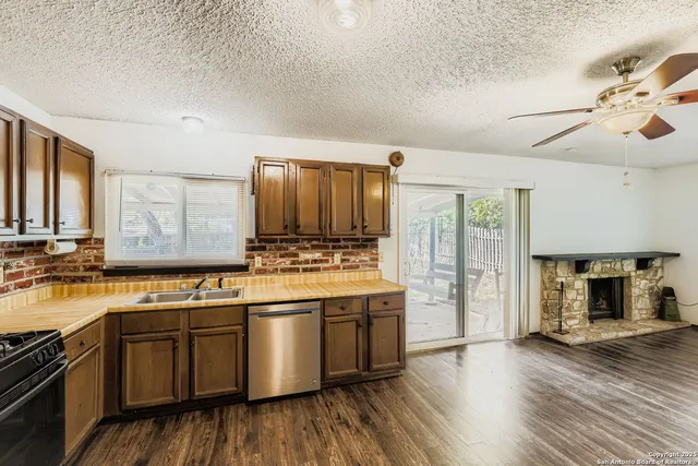 an empty room with wooden floor chandelier fan and windows