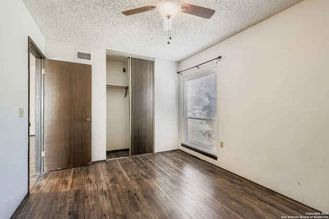 an empty room with a window and a ceiling fan
