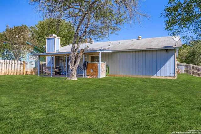 a view of a brick house with a big yard and large trees