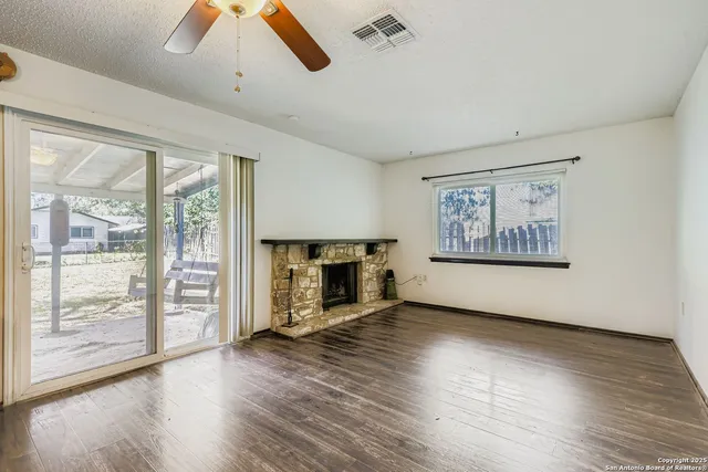 an empty room with wooden floor fireplace and windows