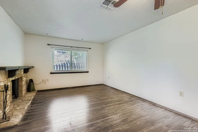 an empty room with wooden floor and a fireplace