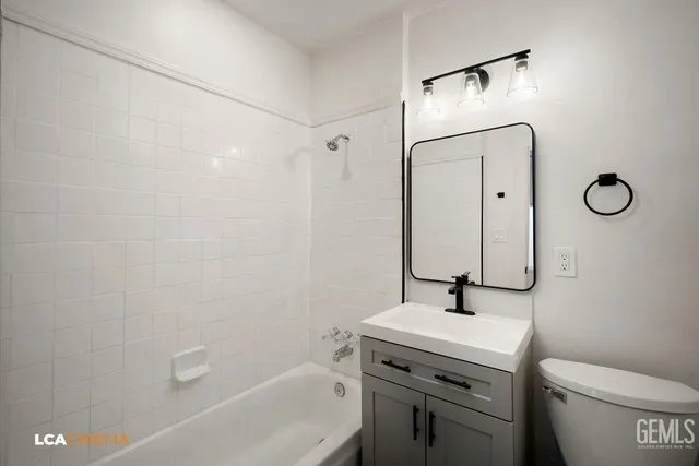 a bathroom with a granite countertop toilet a sink and a mirror