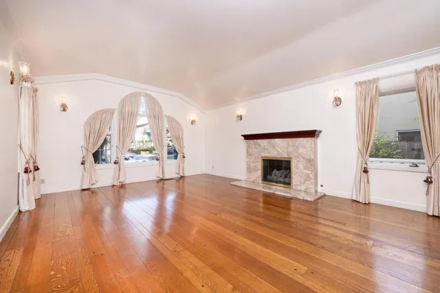 a view of an empty room with window and wooden floor