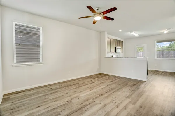 a view of empty room with wooden floor and fan
