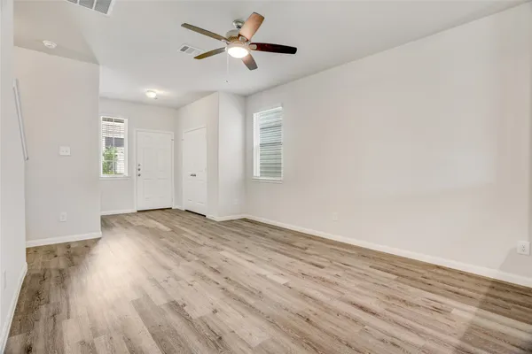 an empty room with wooden floor and windows