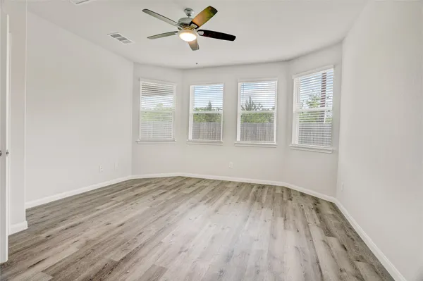 a view of empty room with wooden floor and fan