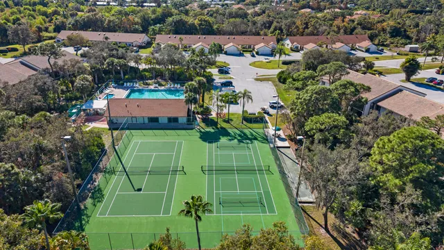 an aerial view of a house with garden space ocean and trees all around