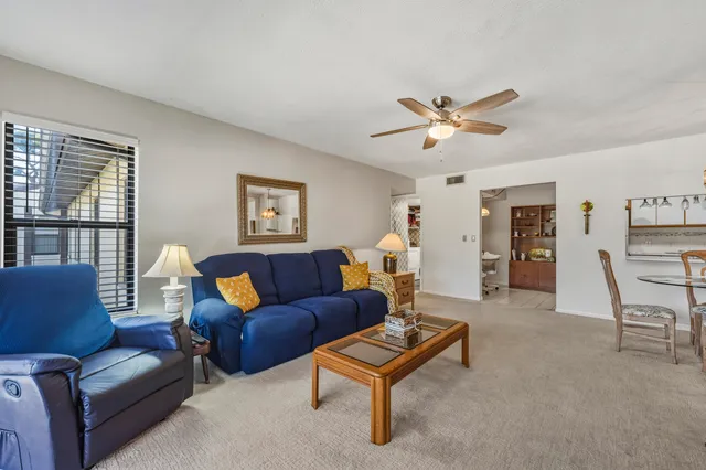 a living room with furniture a ceiling fan and a window