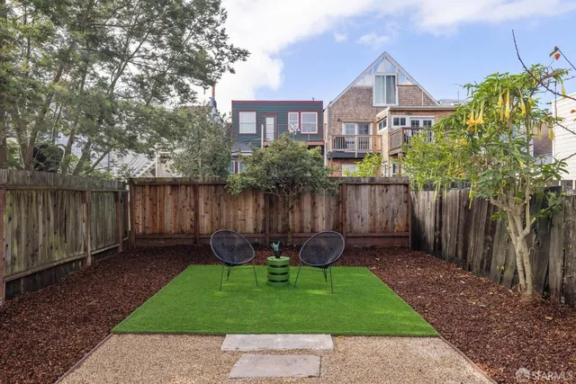 a view of a chair and table in backyard of the house