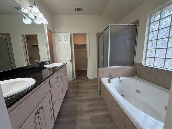 a large bathroom with a tub a double vanity sink and a large mirror